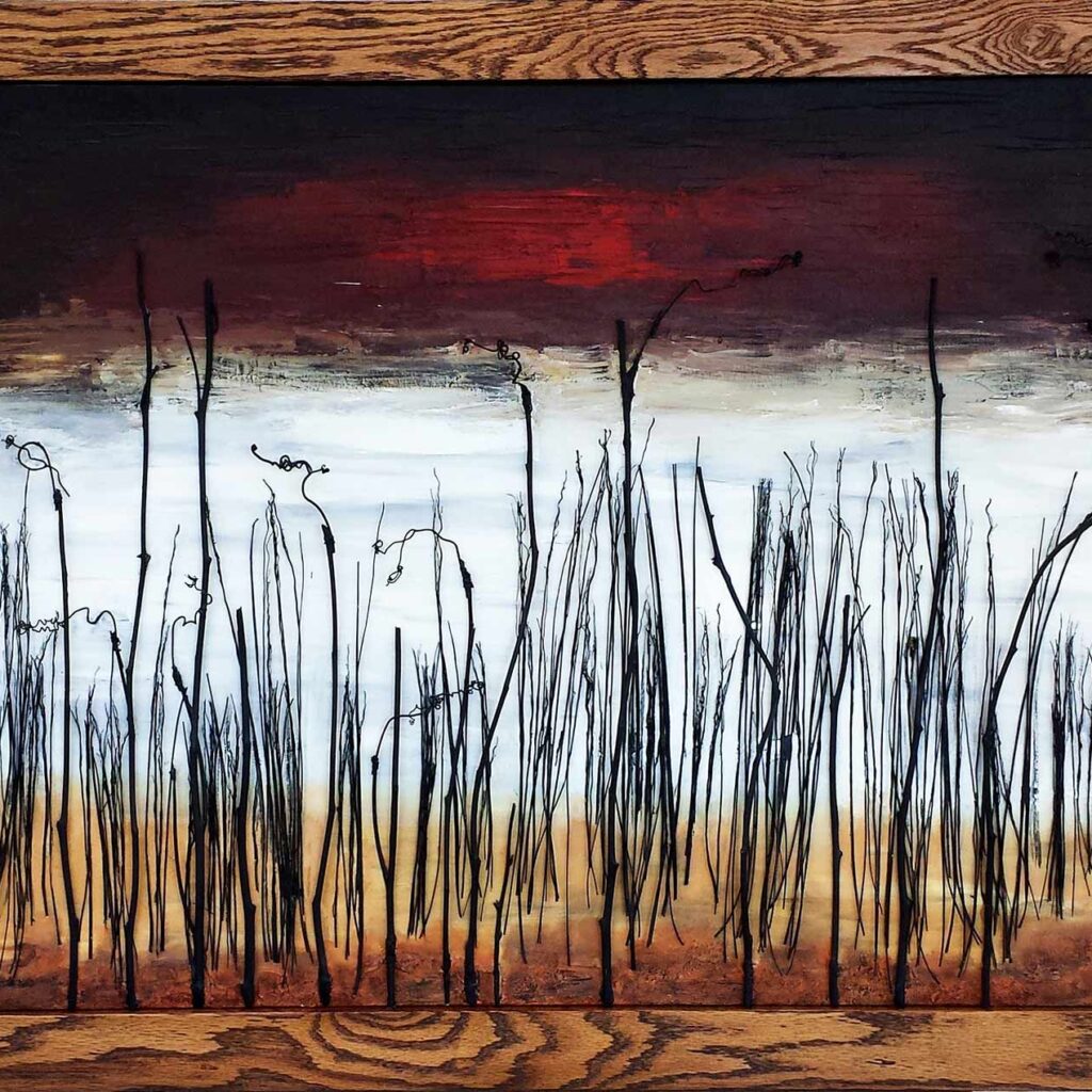 'October Skies' by Alex Sauret is a striking minimalist depiction of a leafless forest. The trees, crafted from real branches, create a tactile, three-dimensional effect. The horizon is rendered in soft white and light blue hues, evoking a sense of calm and distance. In stark contrast, the sky above is painted with dramatic red and black tones, infusing the scene with intense emotion and a hint of foreboding. This juxtaposition of serene and turbulent elements captures the viewer's attention, highlighting the beauty and complexity of nature.